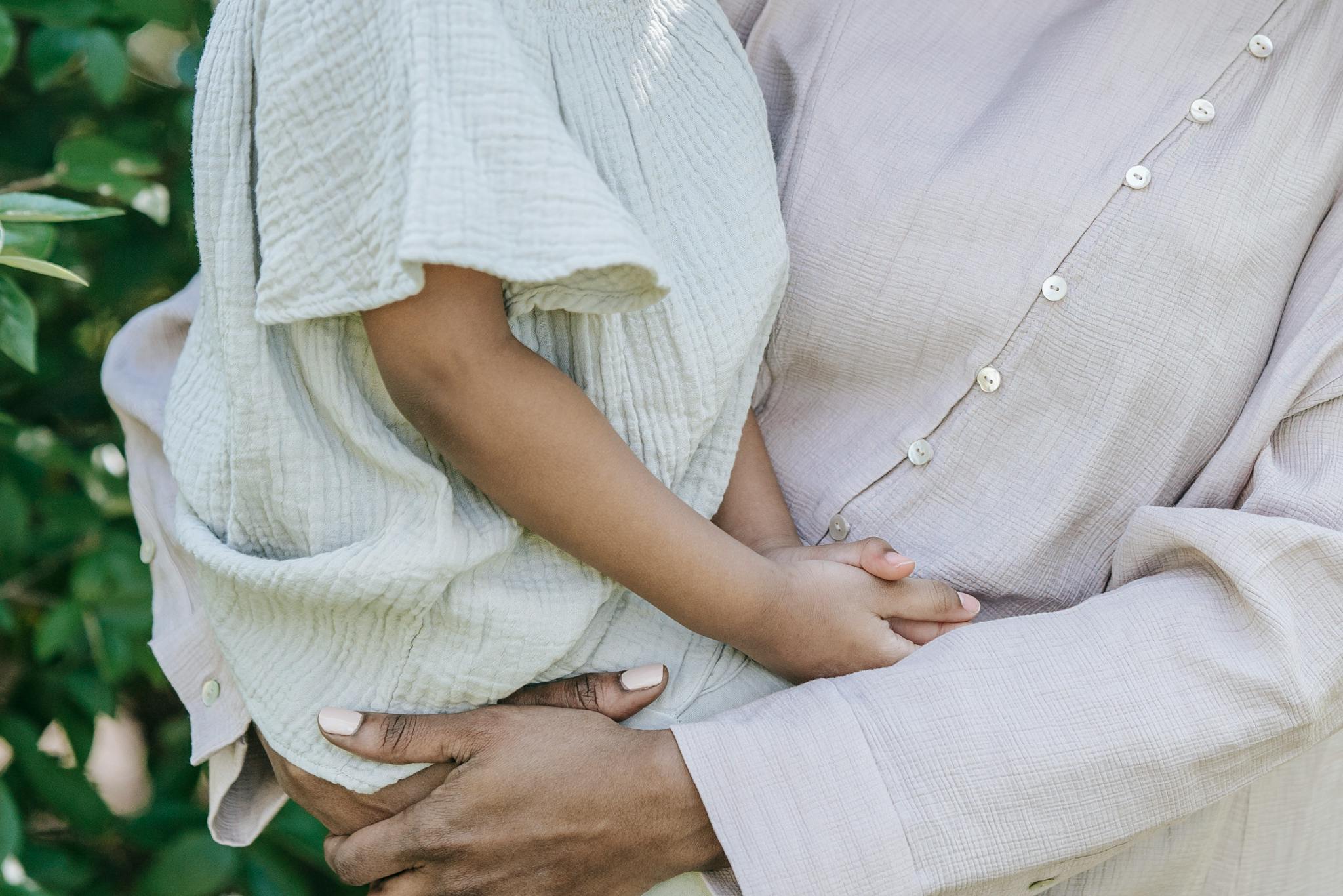 A close-up image of a parent holding a child outdoors, showcasing a tender moment.